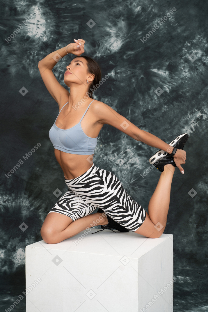 Femme fatiguée en costume de sport qui s'étend ses jambes