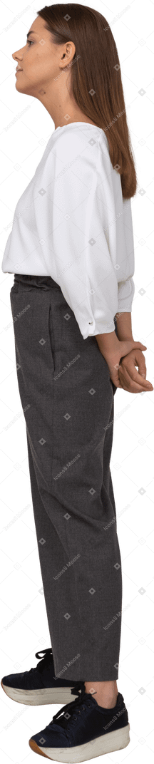 Side view of a young lady in office clothing holding hands behind