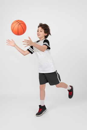 Menino em movimento e jogando uma bola de basquete