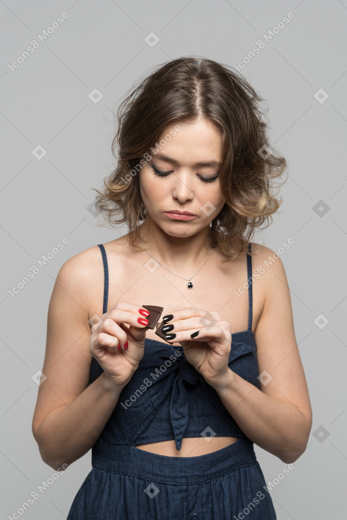 Женщина думает съесть кусочек шоколада
