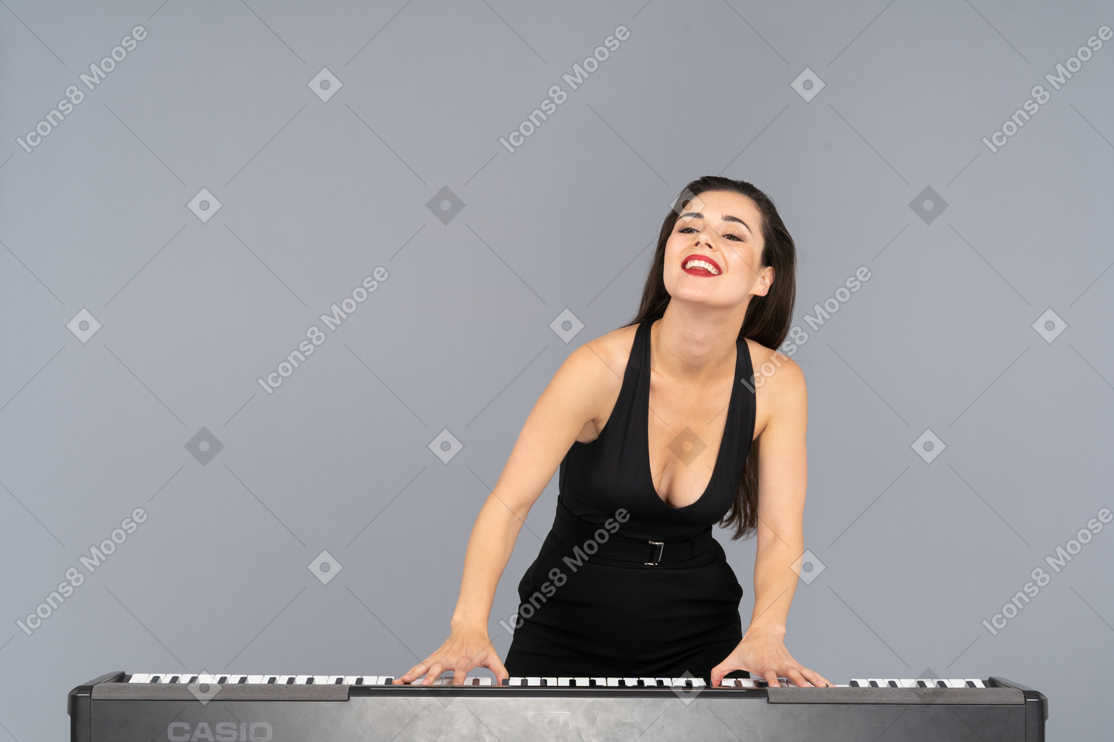 Vue de face d'une jeune femme heureuse en robe noire jouant du piano en souriant
