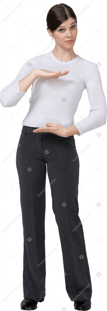 Vista frontal de una mujer joven en ropa de oficina que muestra el tamaño de algo