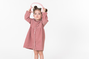 Little girl in pink dress wearing headphones
