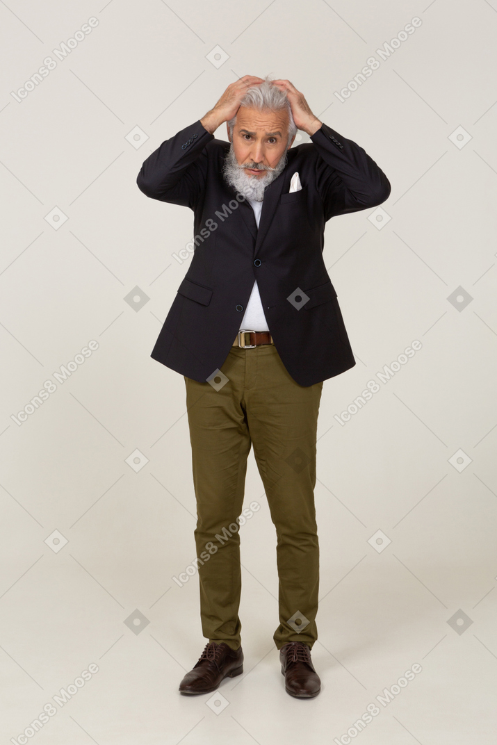 Panicked man in a jacket holding his head