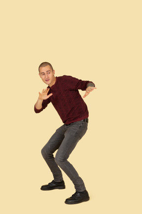 Three-quarter view of a protecting young man dressed in red pullover