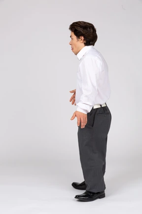 Vista lateral de un joven con ropa informal de negocios mostrando su lengua