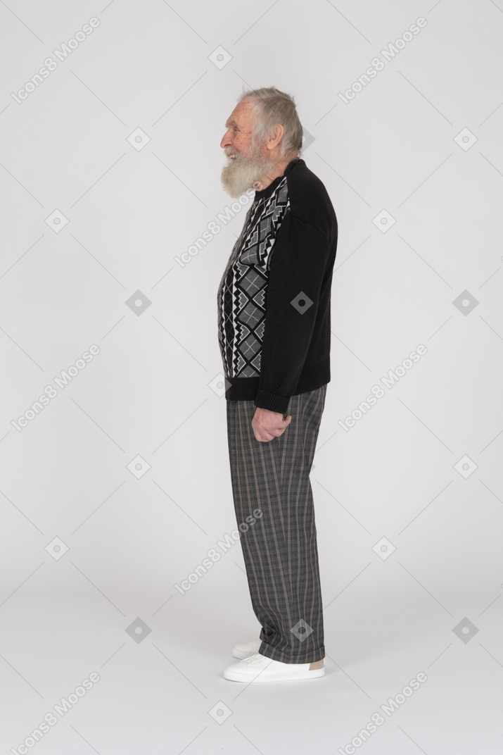 Vista laterale di un vecchio con la barba in piedi e ridendo