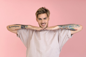 Young man smiling and holding arms down the chin