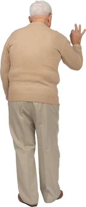 Vista traseira de um velho em roupas casuais, mostrando sinal de ok