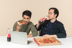 Amigos interraciais comendo junk food e assistindo filme no laptop