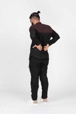 Three quarter back view of a man holding his lower back