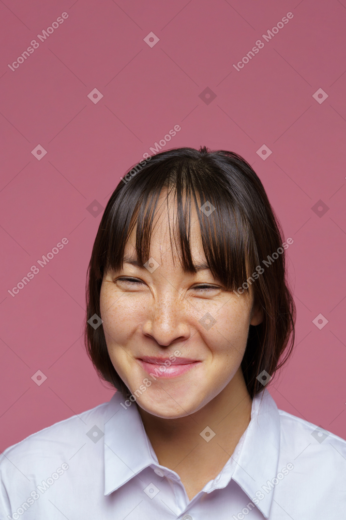 Vue de face d'une femme aux cheveux noirs souriante regardant de côté et rétrécissant les yeux