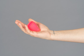 Close up of a hand holding menstrual cup over gray background