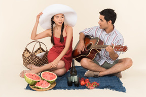 Interracial couple having picnic and man playing on guitar