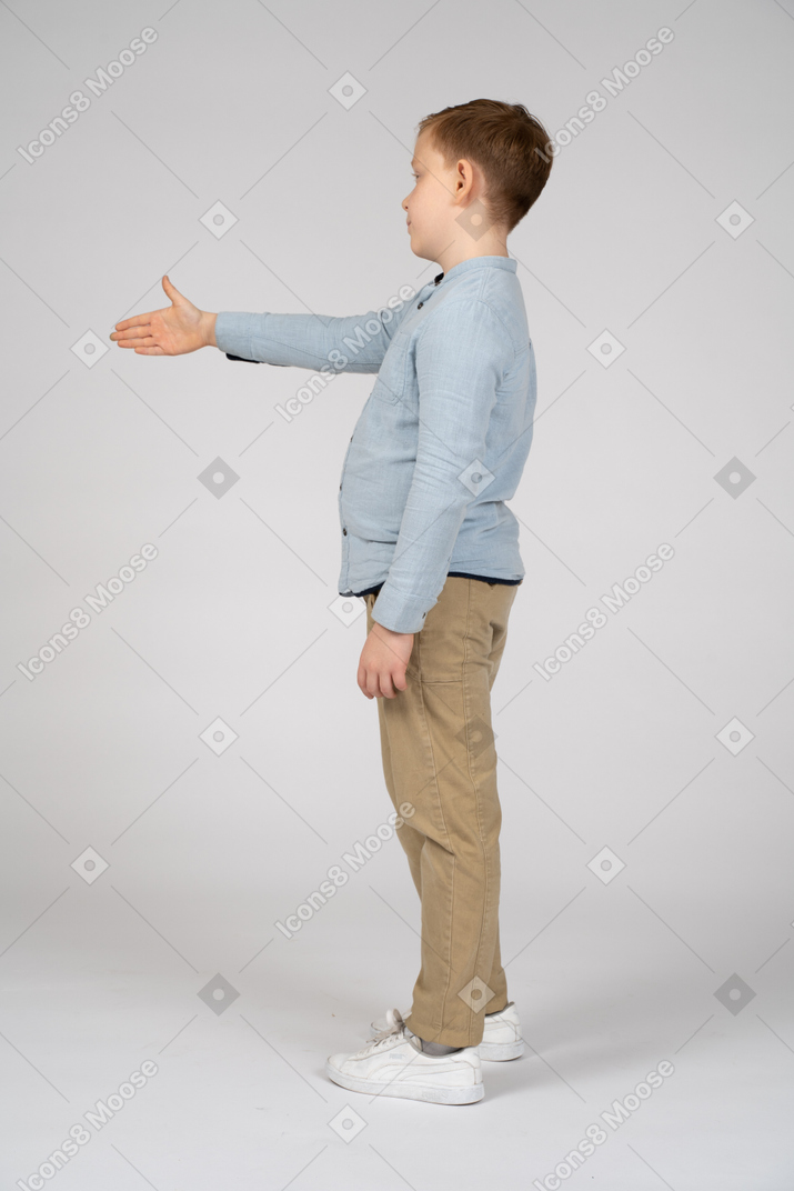 Вид сбоку на мальчика, протягивающего руку для рукопожатия
