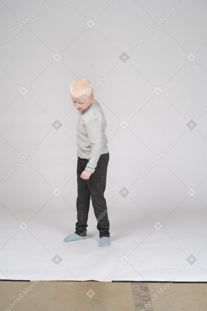 Vista frontal del niño con ropa informal mirando hacia abajo