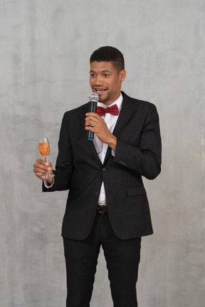 Молодой человек с микрофоном и стаканом предлагает тост