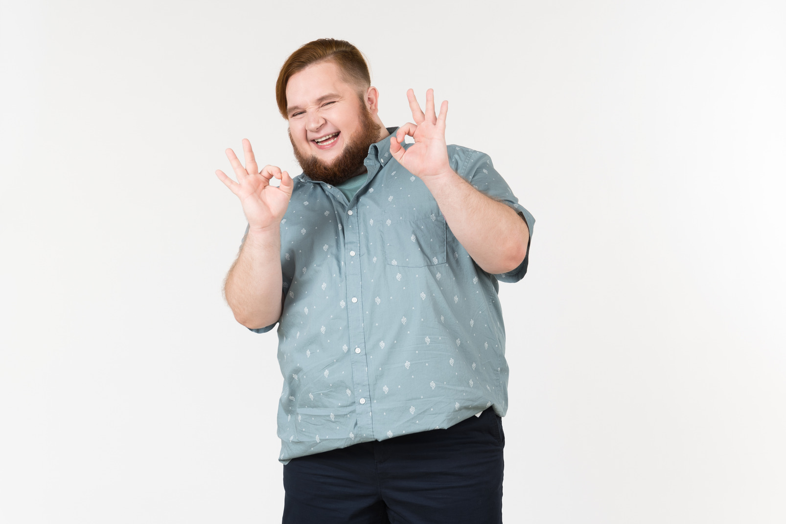 Laughing young overweight man showing ok gesture