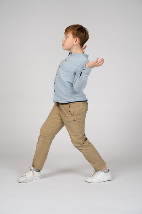 A young boy walking with his hands up