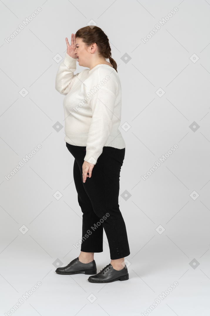 Plump woman in casual clothes looking through imaginary binoculars