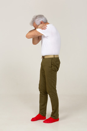 Side view of a man in casual clothes hiding face in arms