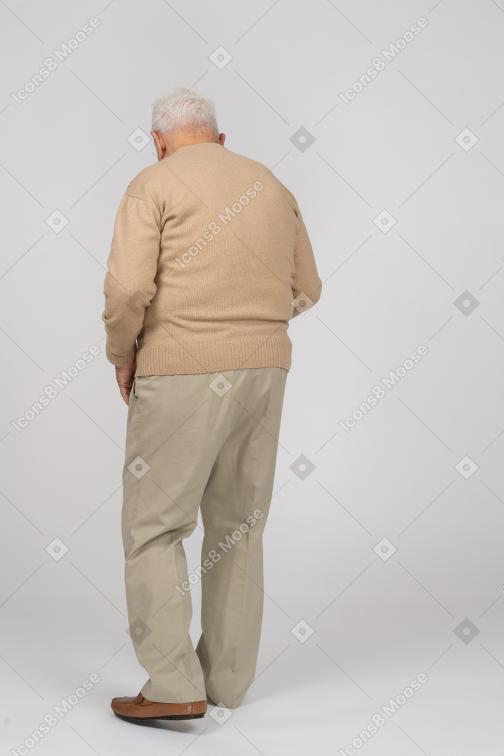 Vista traseira de um velho em roupas casuais andando e olhando para baixo