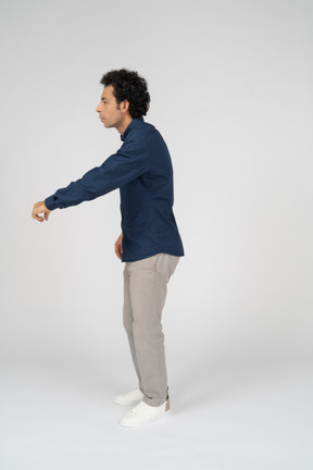 Side view of a man in casual clothes standing with outstretched arm