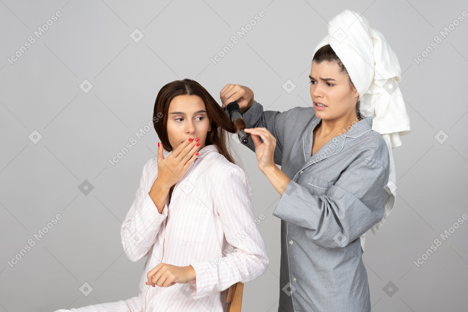 Girl hairstyling her friend's hair  with iron and looks like something went wrong
