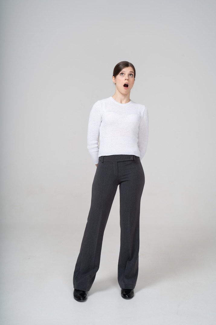Front view of an impressed woman in white blouse and black pants