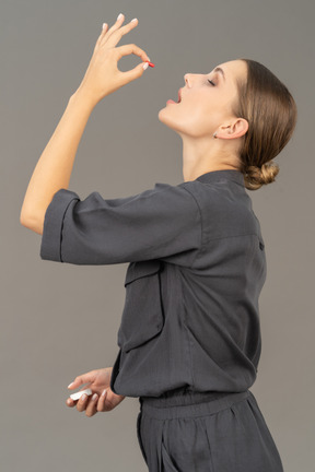 Side view of a young woman in a jumpsuit taking pill