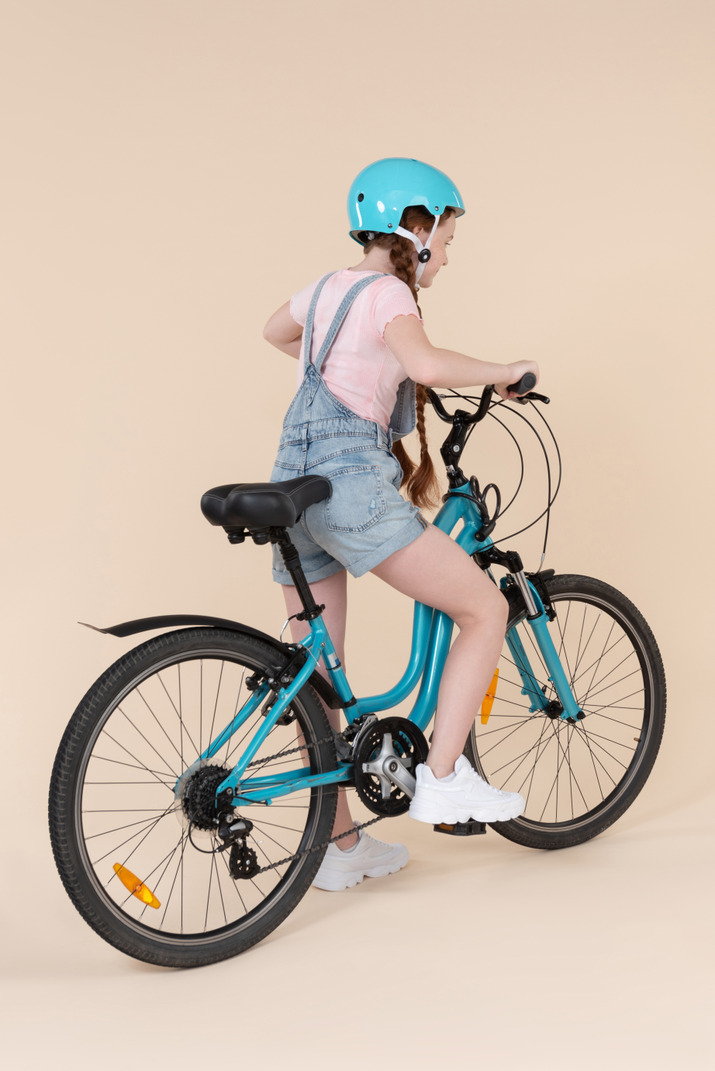 Teenage girl sitting on bicycle back to camera