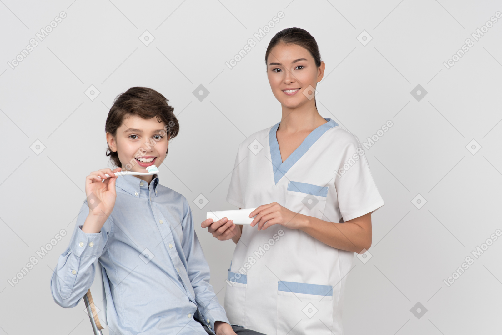 Малыш мальчик пациент держит зубную щетку и женский стоматолог держит зубную пасту