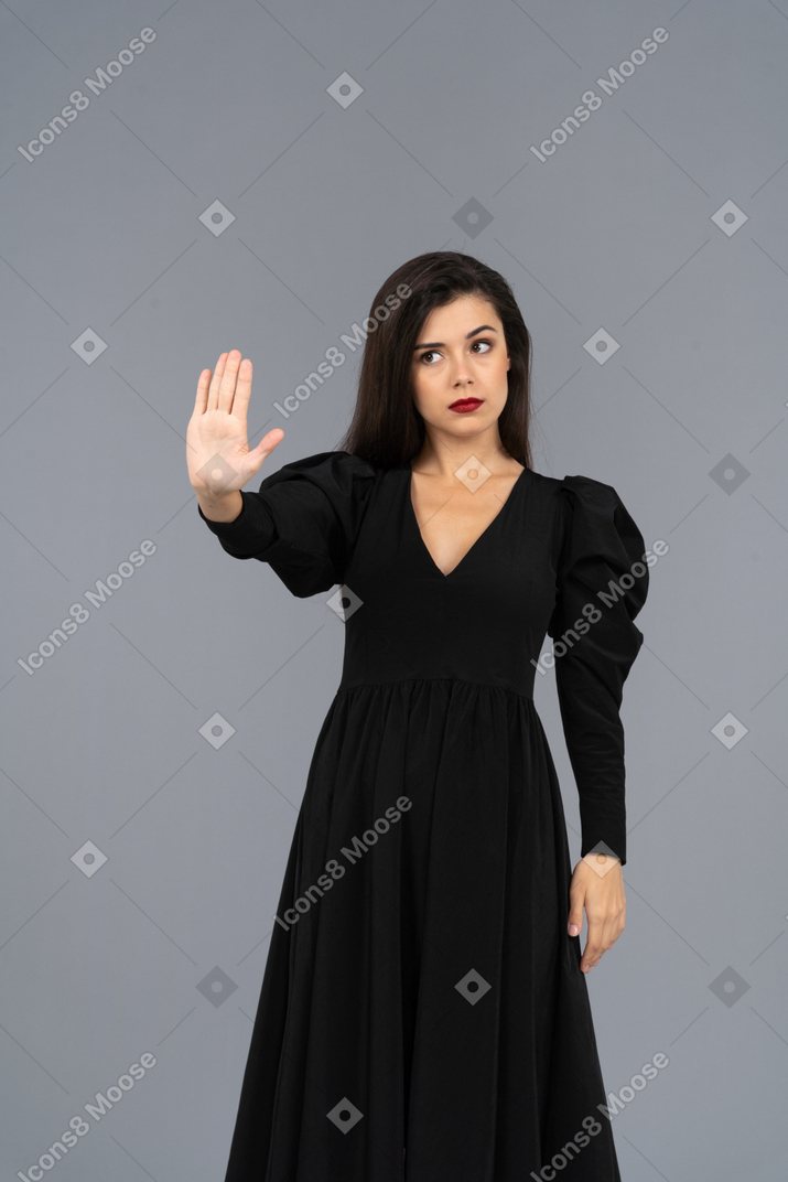 Front view of a young lady in a black dress raising her hand