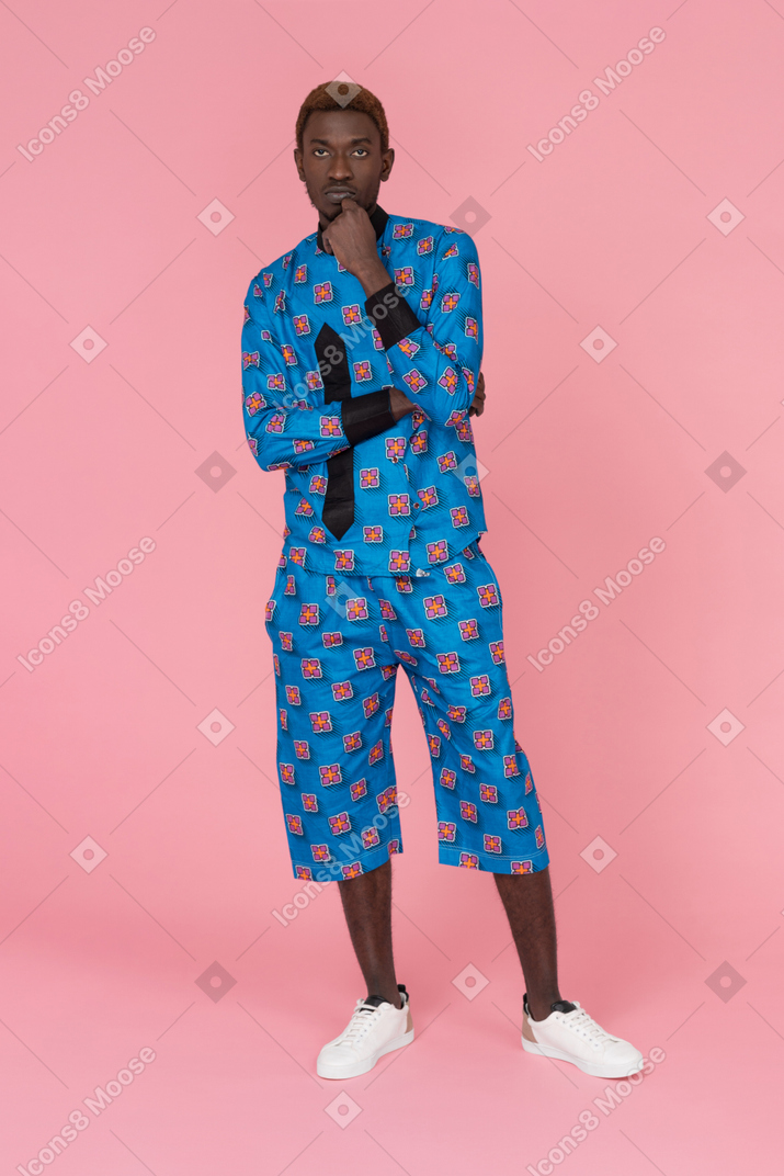 Homem negro de pijama azul em pé sobre fundo rosa