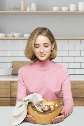 A woman holding a bowl with mushrooms in it