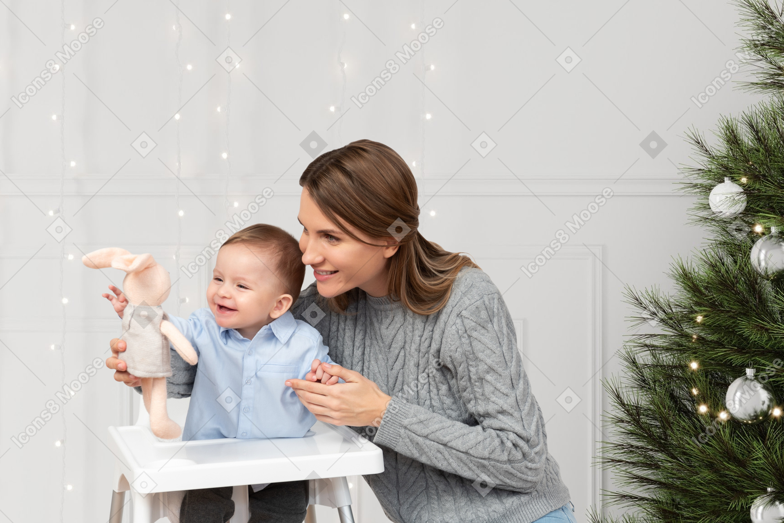 A mother and her baby are playing with a christmas tree