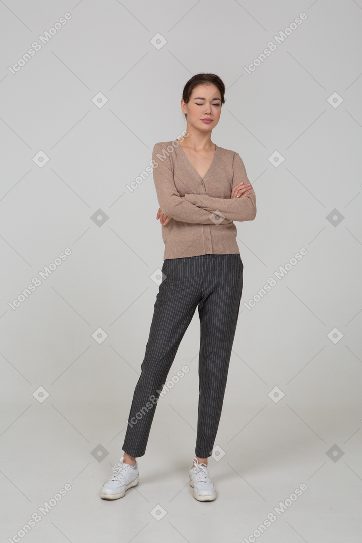 Vista frontale di una giovane donna prepotente in maglione beige attraversando le mani