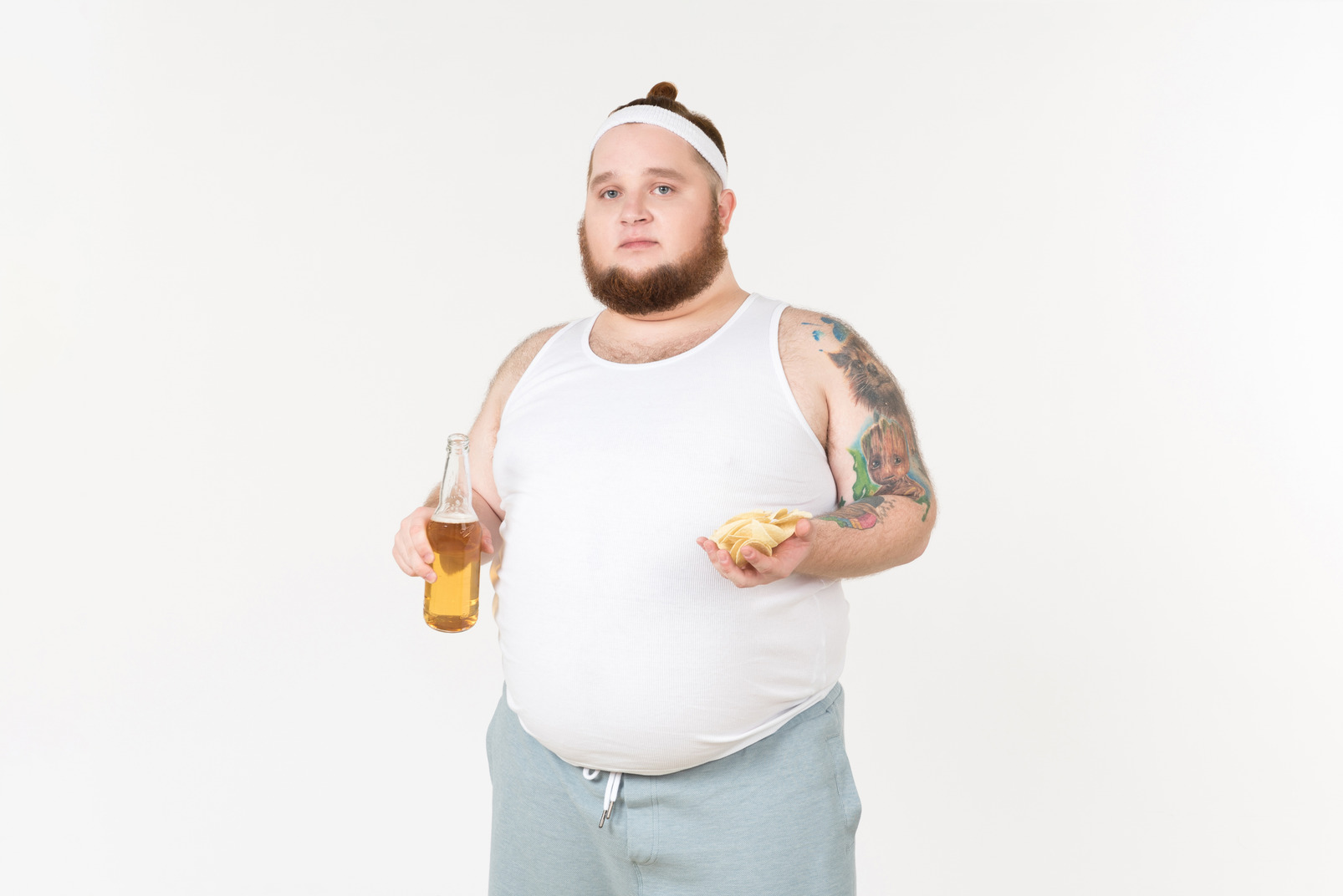 A fat man in sportswear holding a bottle of beer and potato chips