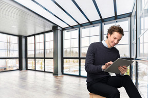 A man sitting on a stool looking at a tablet