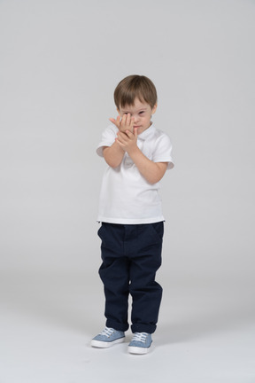 Front view of a little boy covering his eye