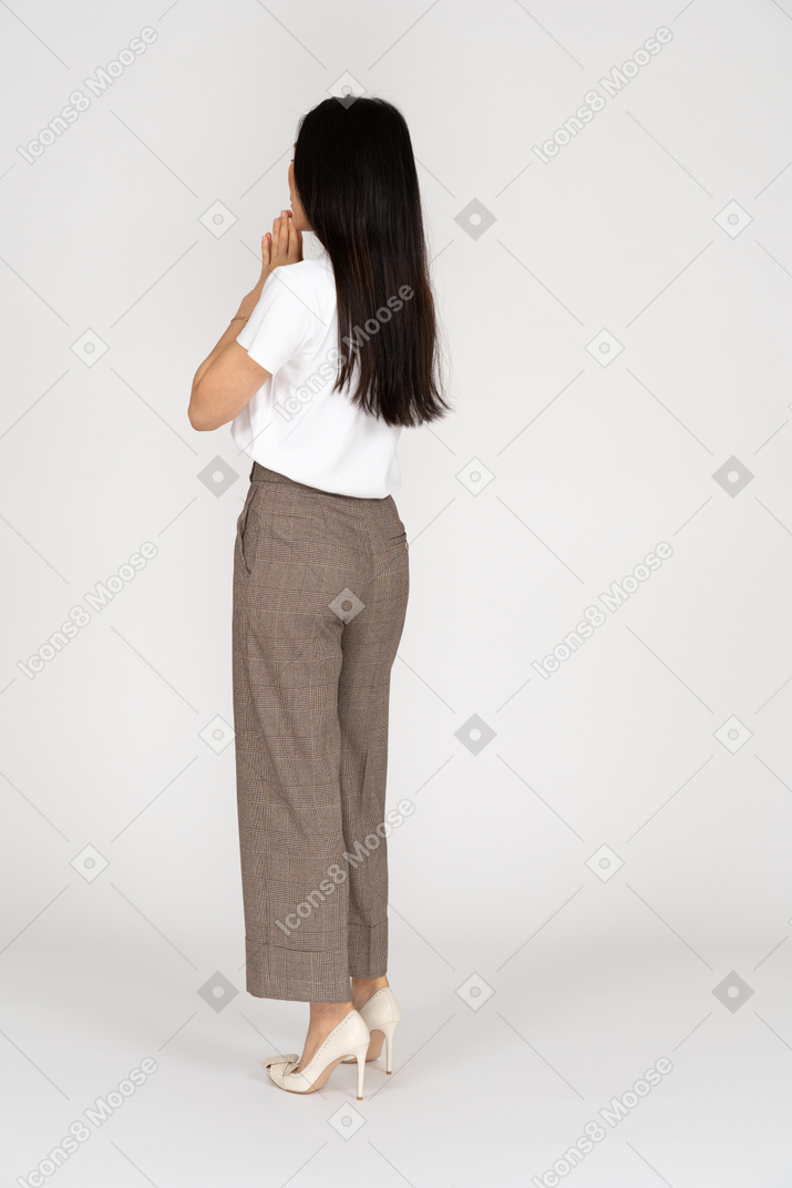 Dreiviertel-rückansicht einer jungen dame in reithose und t-shirt, die hände zusammenhalten
