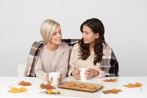 Mulheres jovens tomando café e olhando uns aos outros