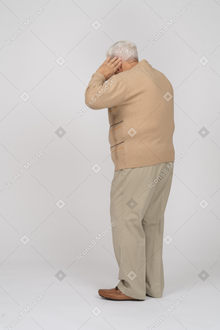 Старик в повседневной одежде держит руку близко к уху