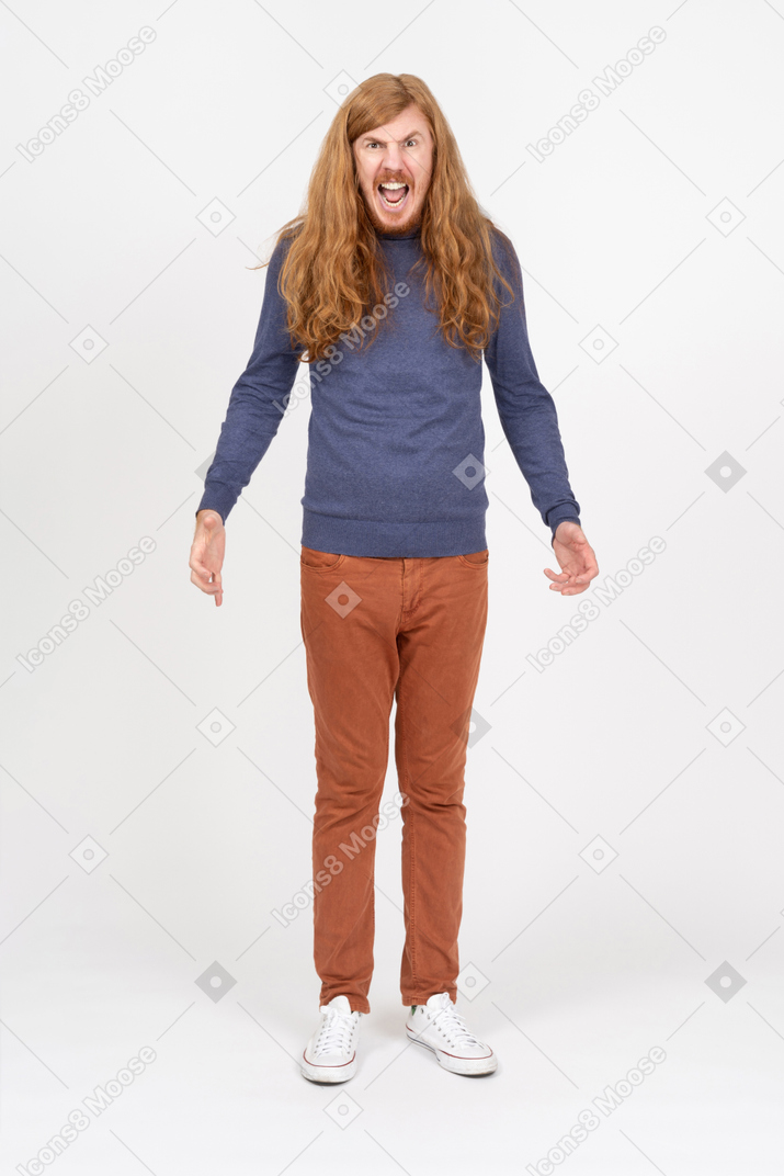 Vue de face d'un jeune homme émotif dans des vêtements décontractés debout avec les bras tendus et regardant la caméra