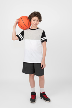 Boy holding basketball ball on his shoulder