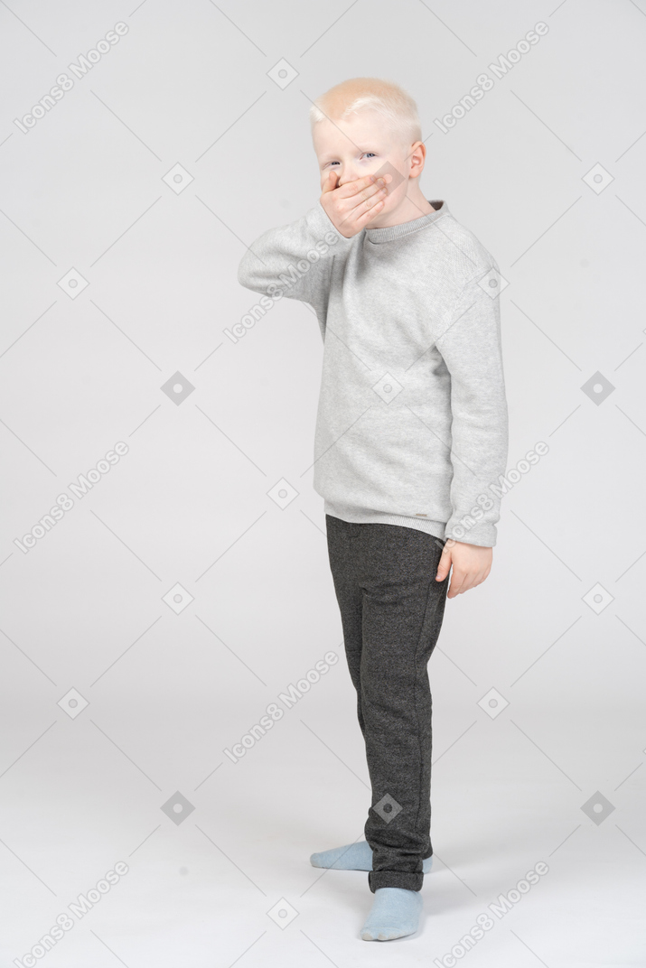 Boy in casual clothes covering his mouth with hand
