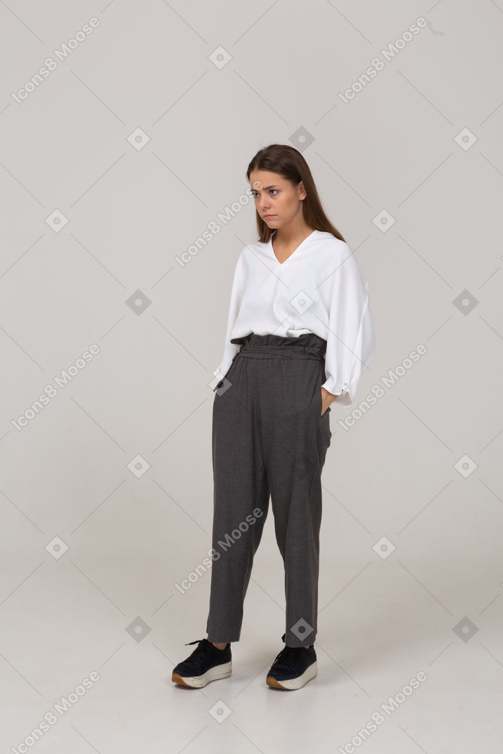 Vista di tre quarti di una giovane donna in abiti da ufficio che mette le mani in tasca