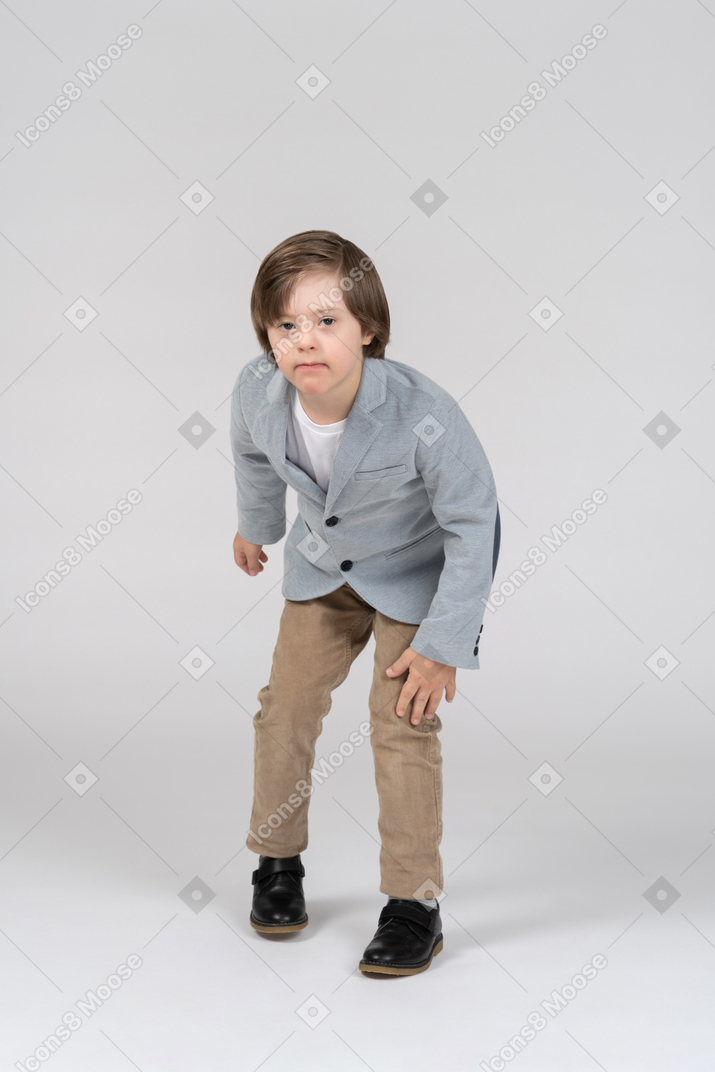 Young boy in gray jacket and khaki pants leaning forward
