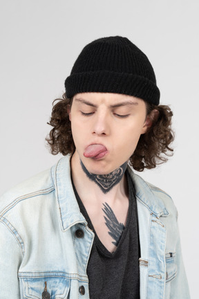 Teenager in a knit hat showing his tongue