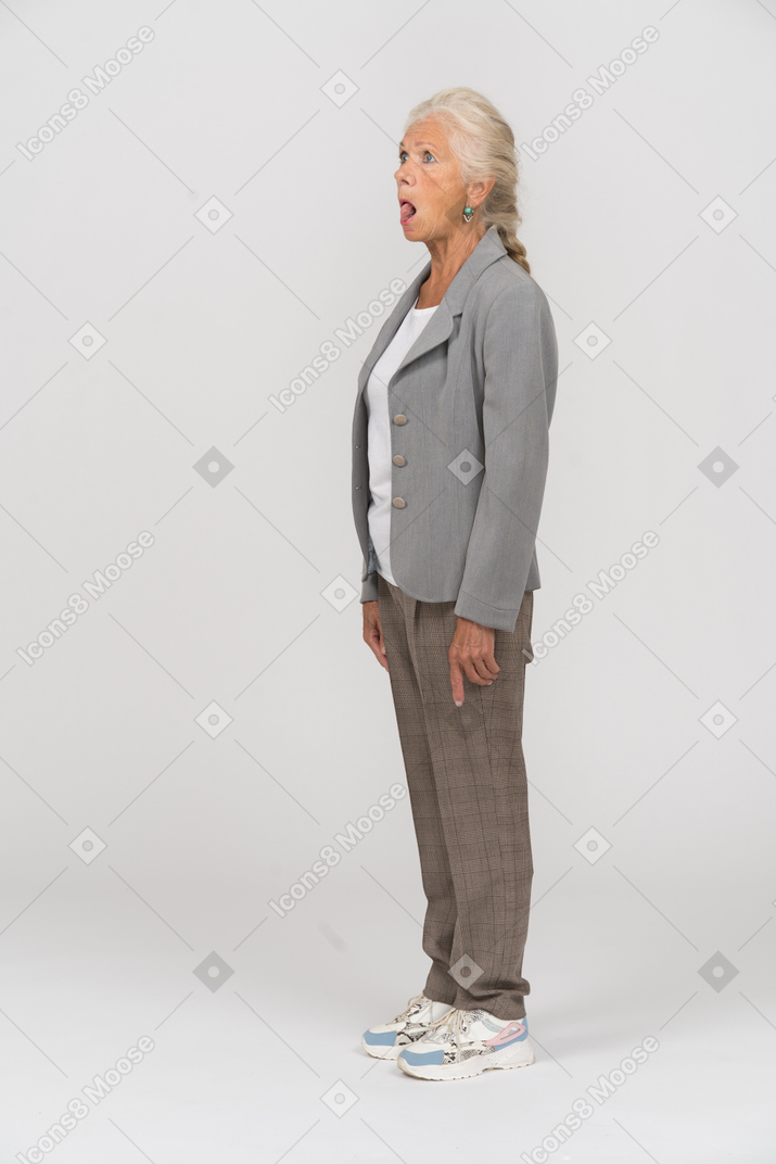 Vista lateral de uma senhora idosa de terno mostrando a língua